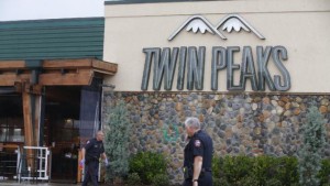 Waco police officers walk along the perimeter of Twin Peaks restaurant during an investigation Wednesday, May 20, 2015 in Waco, Texas.  A deadly weekend shootout involving rival motorcycle gangs apparently began with a parking dispute and someone running over a gang member's foot, police said Tuesday.  (Rod Aydelotte/Waco Tribune Herald, via AP)